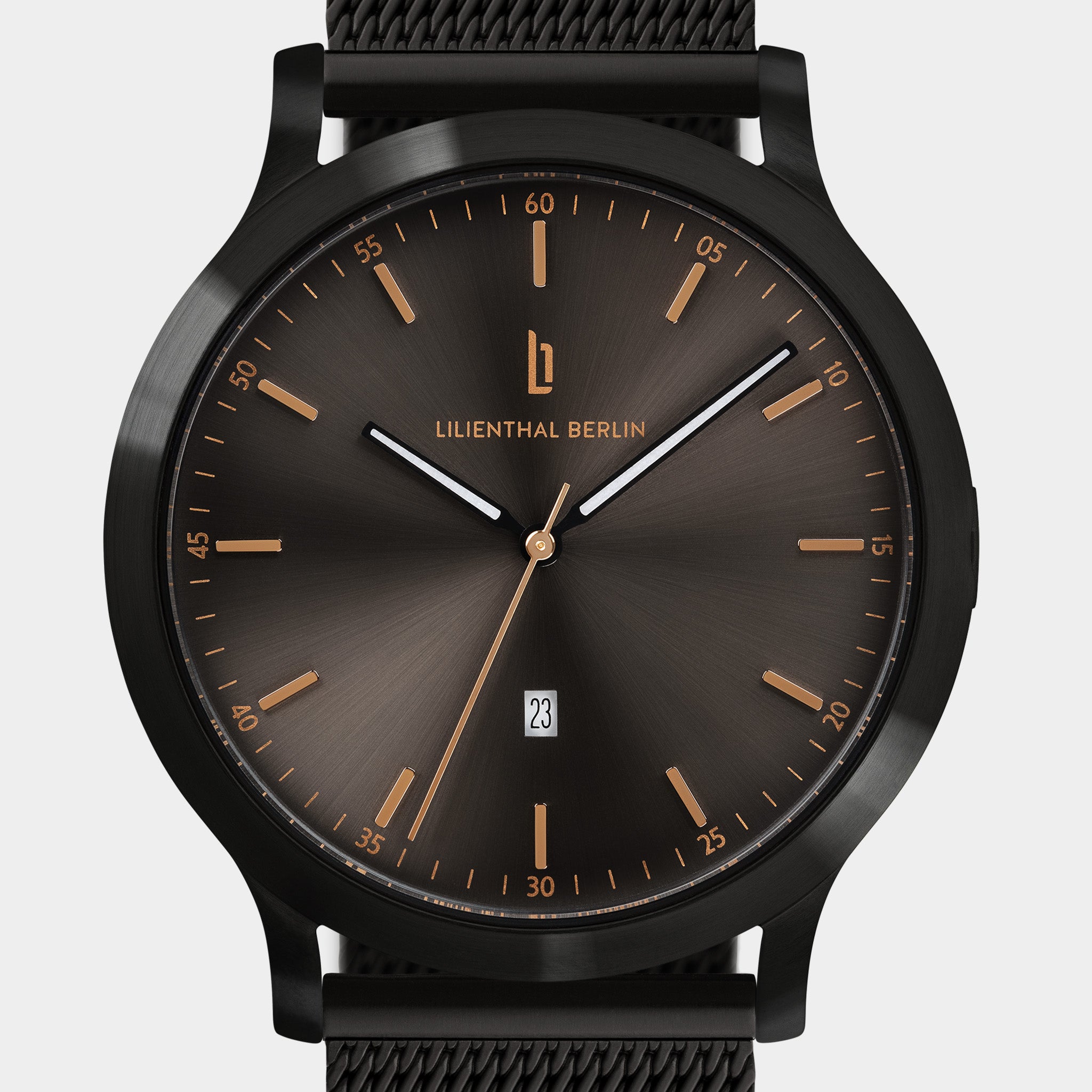 Black mesh band watch with dark sunray dial, gold indices, and date display at six o'clock