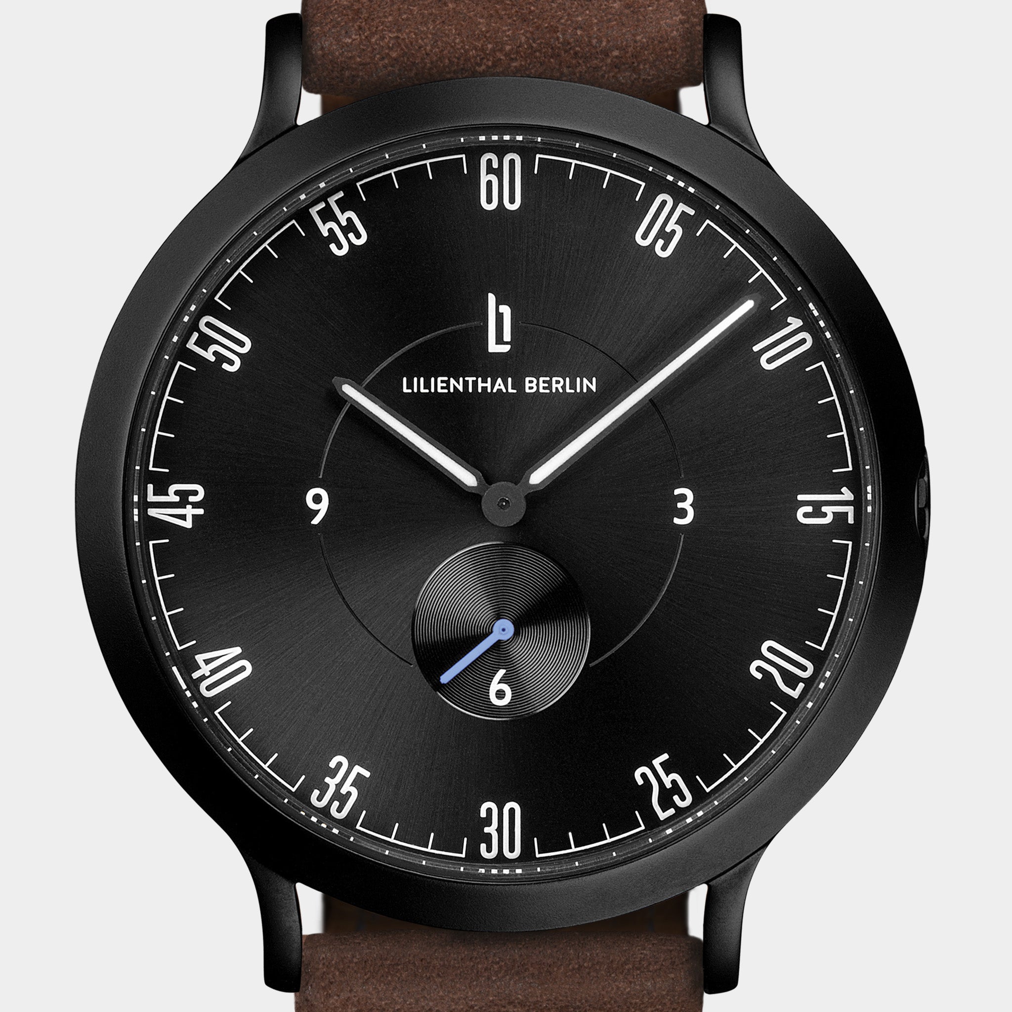 Black minimalist wristwatch with brown leather strap, bold white numerals, and small seconds subdial