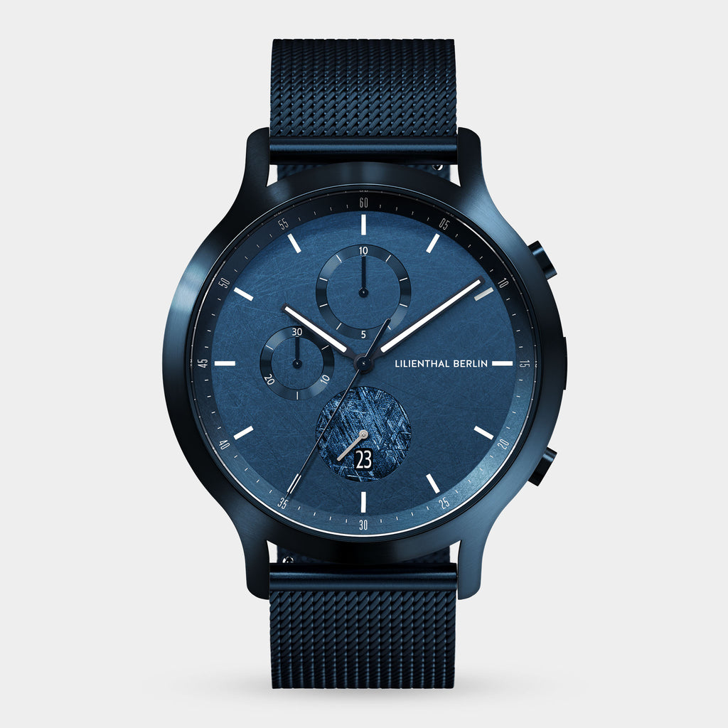 Blue chronograph watch with mesh strap, modern dial, and visible date display.