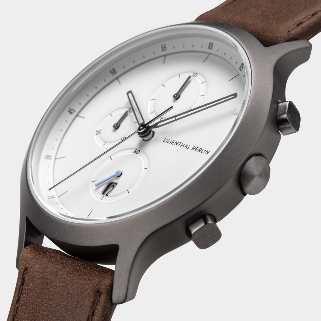 Minimalist chronograph watch with white dial, brown leather strap, and stainless steel case