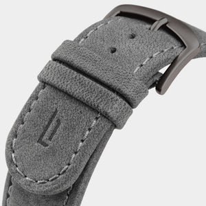 Close-up of a grey suede watch strap with stitching and metal buckle