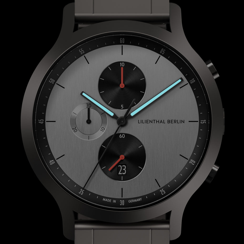 Modern chronograph watch with grey dial, black sub-dials, date window, and luminous hands