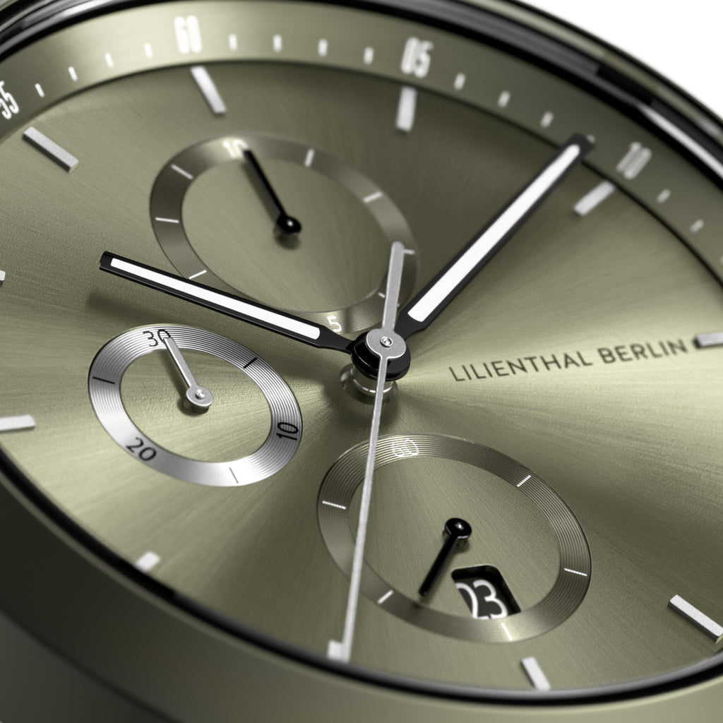 Close-up of a modern chronograph watch face with metallic olive dial and subdials