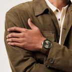 Man wearing green chronograph watch with suede jacket and cream shirt