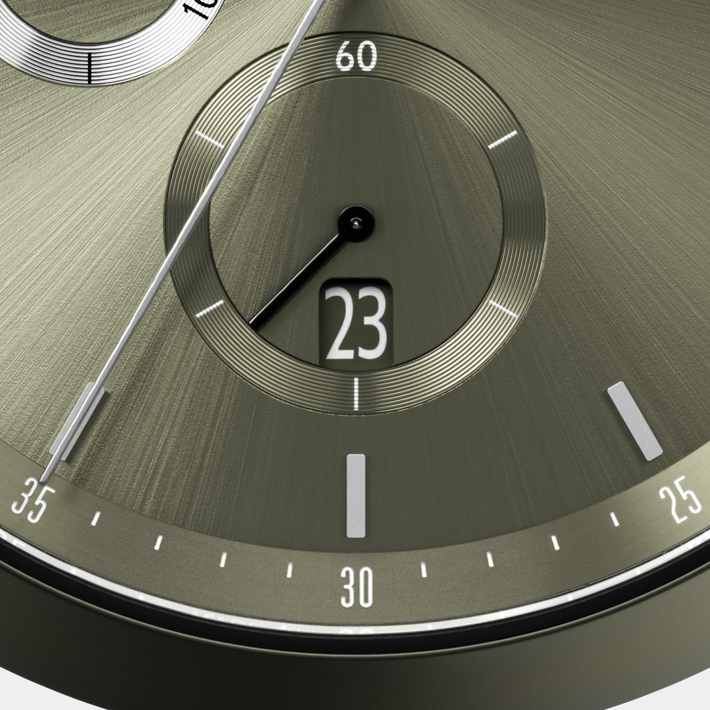 Close-up of olive green watch face with date window, silver markers, and subdial.