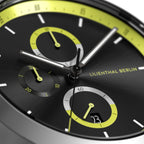 Close-up of modern black chronograph watch face with yellow accents and subdials