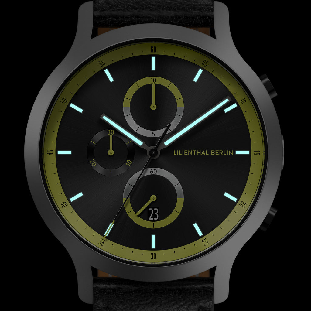 Black chronograph watch with green accents, luminous hands, subdials, and date display