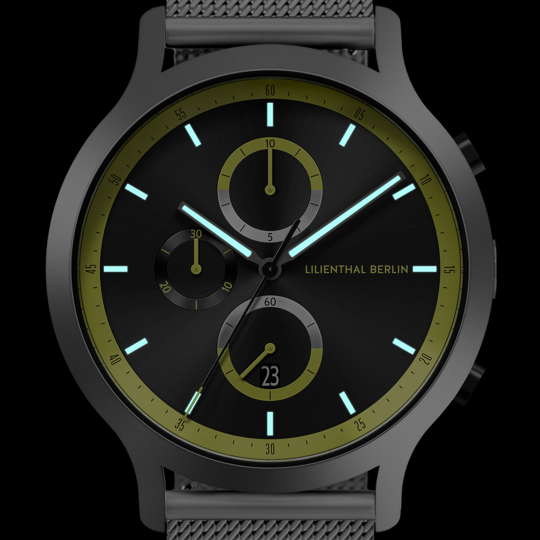 Modern black chronograph watch with green accent markers, mesh strap, and luminous hands