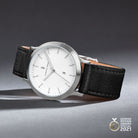 Minimalist silver watch with white dial, black leather strap, date window, award logo.