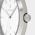 Close-up of minimalist silver wristwatch with brushed metal case and white dial