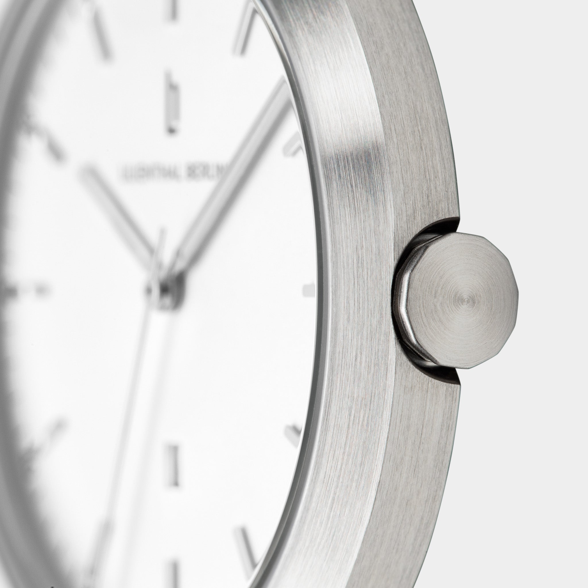 Minimalist silver wristwatch with brushed stainless steel case, white dial, and sleek crown