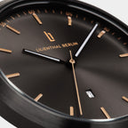 Close-up of a minimalist black watch face with gold markers and date display