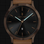 Elegant black dial wristwatch with gold case, date window, and light brown leather strap