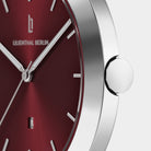 Close-up of silver minimalist watch with red dial and date display