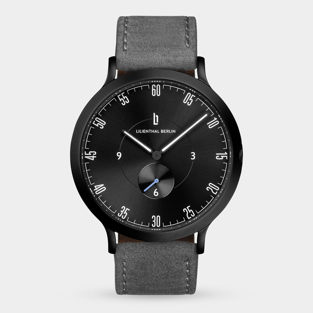 Minimalist black watch with grey leather strap, black dial, and white markers