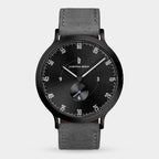 Minimalist black watch with grey leather strap, black dial, and white markers
