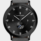 Minimalist black analog watch with white markers, grey strap, subdial, and modern design.