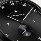 Close-up of a black minimalist watch face with white hands and Lilienthal Berlin logo.
