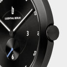 Close-up of a black minimalist wristwatch face with white hands and hour markers