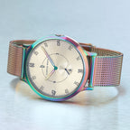 Elegant mesh band watch with metallic rainbow bezel and minimalist dial on a silver surface