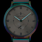 Minimalist analog watch with iridescent case and mesh strap, black dial, luminous hands