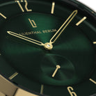 Close-up of green watch face with gold hands and markers, modern minimalist design